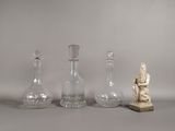 trois vases en verre et une petite statue posés sur une table