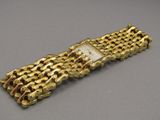 gros plan d'un bracelet en or sur une surface grise