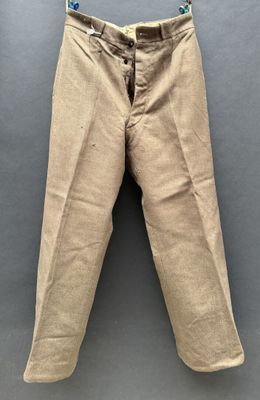 un gros plan sur un pantalon beige posé sur une surface grise