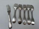 six forks and a knife are lined up on a table