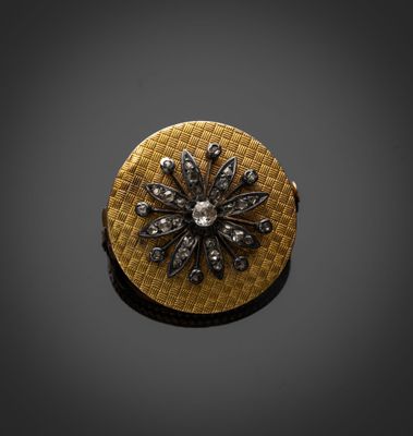 une photo d'une broche en or et diamants posée sur une surface noire