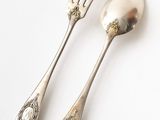 two silver spoons and a fork on a white surface