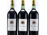 trois bouteilles de vin rouge sont alignées sur une surface blanche