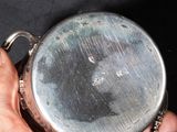 a person holding a silver pocket watch in their hand