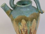 a blue and green vase with a handle on it