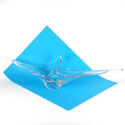 un morceau de papier bleu sur lequel est posé un bol en verre