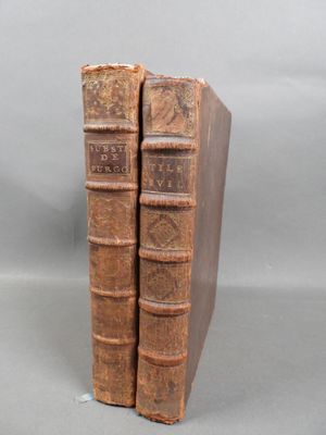 two old books sitting on top of each other on a table