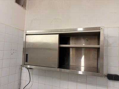 une armoire en acier inoxydable dans une salle de bains carrelée de blanc