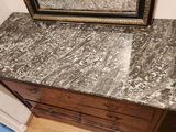un miroir posé sur une commode au plateau en marbre
