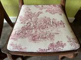 a wooden chair with a pink and white toile fabric on it