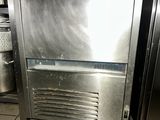 a small stainless steel refrigerator in a kitchen with a lot of dirty flooring