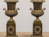 pair of antique bronze urns on pedestals on a table