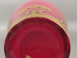 un gros plan sur un vase en verre rouge orné d'une bordure dorée