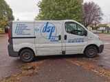 a white van parked in a parking lot with trees in the background