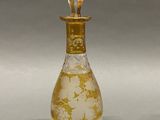 a glass bottle with a gold decoration on it