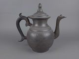 an old silver teapot with a metal handle on a gray background