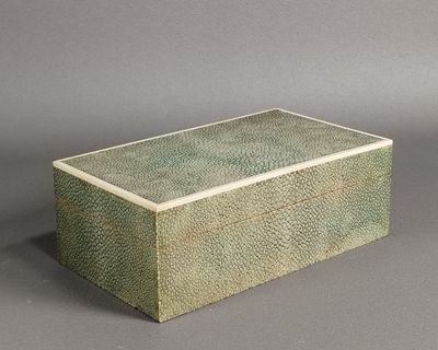 une image représentant une boîte verte avec un couvercle posée sur une surface grise