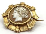 une image représentant une broche dorée et blanche avec une tête de femme au centre
