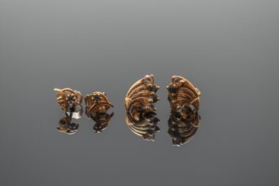 trois paires de boucles d'oreilles en or et diamants posées sur une surface grise