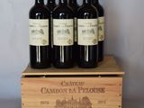 quatre bouteilles de vin rouge dans une caisse en bois posée sur une table