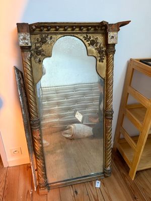 a mirror sitting on the floor next to a shelf