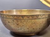 a gold bowl sitting on a table next to a plate