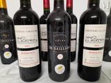six bottles of red wine are lined up on a table