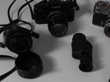 several cameras and a cell phone sitting on a table