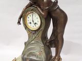 une statue en bronze représentant une femme appuyée contre une horloge