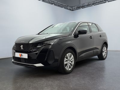 Une voiture noire est garée dans une grande pièce aux murs blancs.