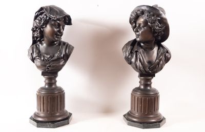 une paire de bustes en bronze représentant une femme et un homme, posés sur des socles