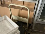 a white cart sitting next to a stack of boxes on a floor