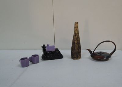 un vase, une théière, une autre théière et des tasses posées sur une table