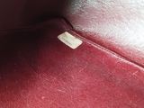 a close up of a red leather bag with a tag on it