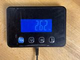 a digital clock on a table with a charger