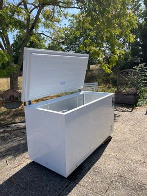 un congélateur coffre blanc posé au bord de la route