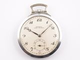 une montre de poche en argent posée sur une surface blanche