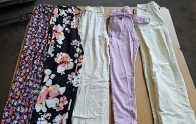 de nombreux pantalons de différentes couleurs posés sur une table dans une pièce