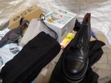 a pair of black shoes sitting on a bed next to a box of clothes