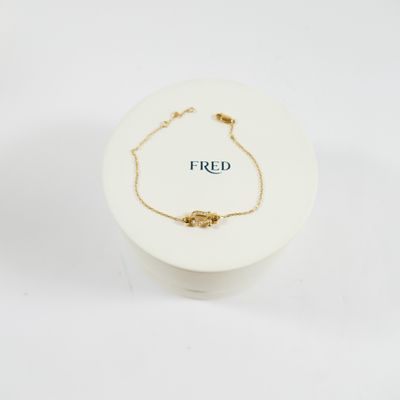 un gros plan sur un bracelet en chaîne dorée portant l'inscription « fred »