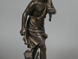 an antique bronze statue of a woman holding a bird on a rock