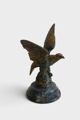 bronze statue of a bird on a pedestal with a white background
