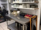 a kitchen with a stainless steel table and shelves filled with dishes