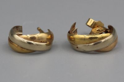 paire de boucles d'oreilles dorées, avec un motif torsadé sur fond gris