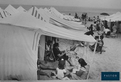 photo en noir et blanc d'un groupe de personnes assises dans des tentes sur une plage
