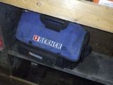 un sac à outils bleu posé sur une étagère dans un garage