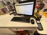 a computer desk with a keyboard, mouse, and a cell phone on it