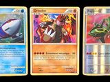Trois cartes Pokémon différentes sont représentées en rangée sur un fond noir