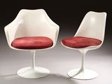 pair of white tulip chairs with red cushions in a dark room