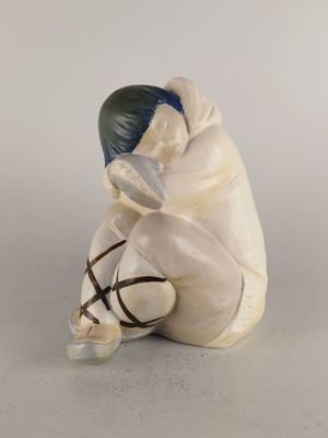 figurine représentant un homme assis par terre avec un sac d'argent